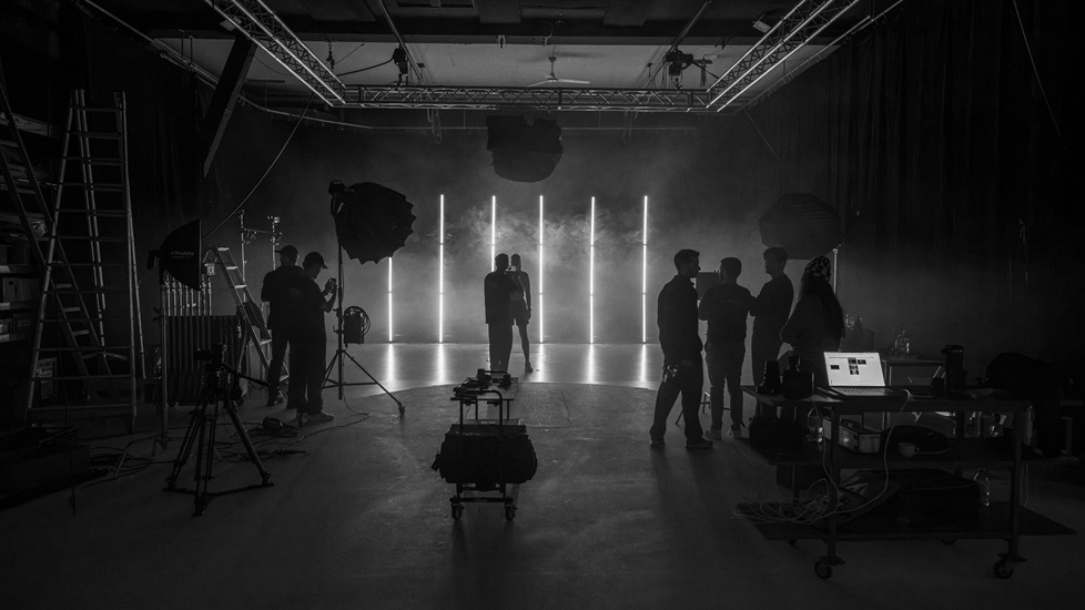Ein Fotostudio mit mehreren Personen, die an einem Set mit Lichtstreifen und Nebel arbeiten. Es handelt sich dabei um eine behind the scenes-Aufnahme aus dem Mietstudio für Film- und Fotoproduktionen StudioGutenswil in der Nähe von Zürich (Schweiz).